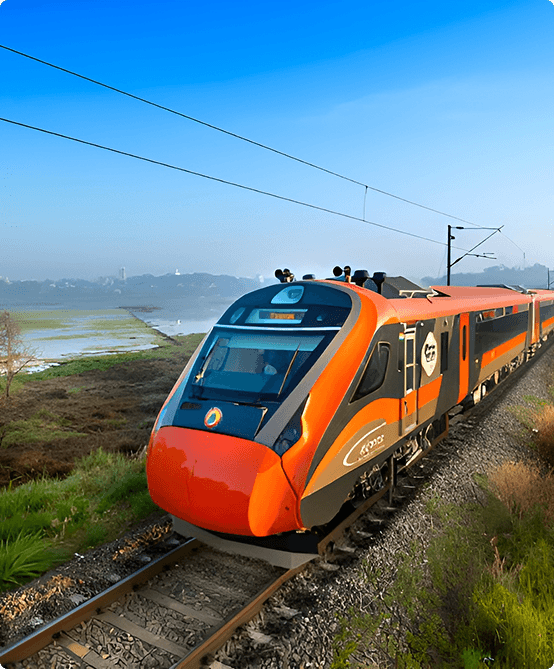 Modern orange and black passenger train running on a railway track with green fields and clear sky in background